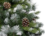 Albero di Natale verde con pigne e neve.