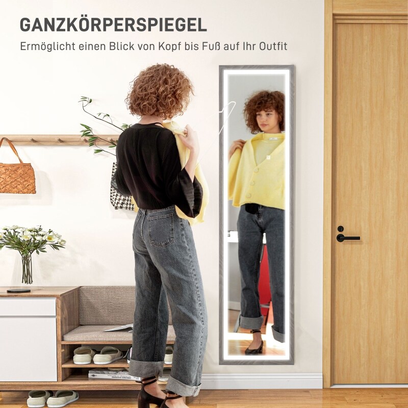 Eine Frau prüft ihr Outfit in einem beleuchteten Ganzkörperspiegel.