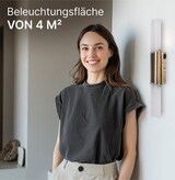 Eine Frau steht vor einer Wand mit einer Lampe.