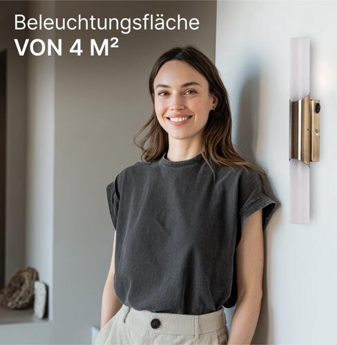 Eine Frau steht vor einer Wand mit einer Lampe.