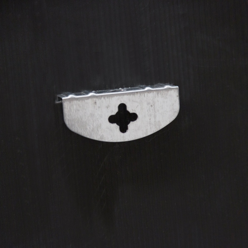 Ein kleiner Metallclip mit einem kreuzförmigen Loch.