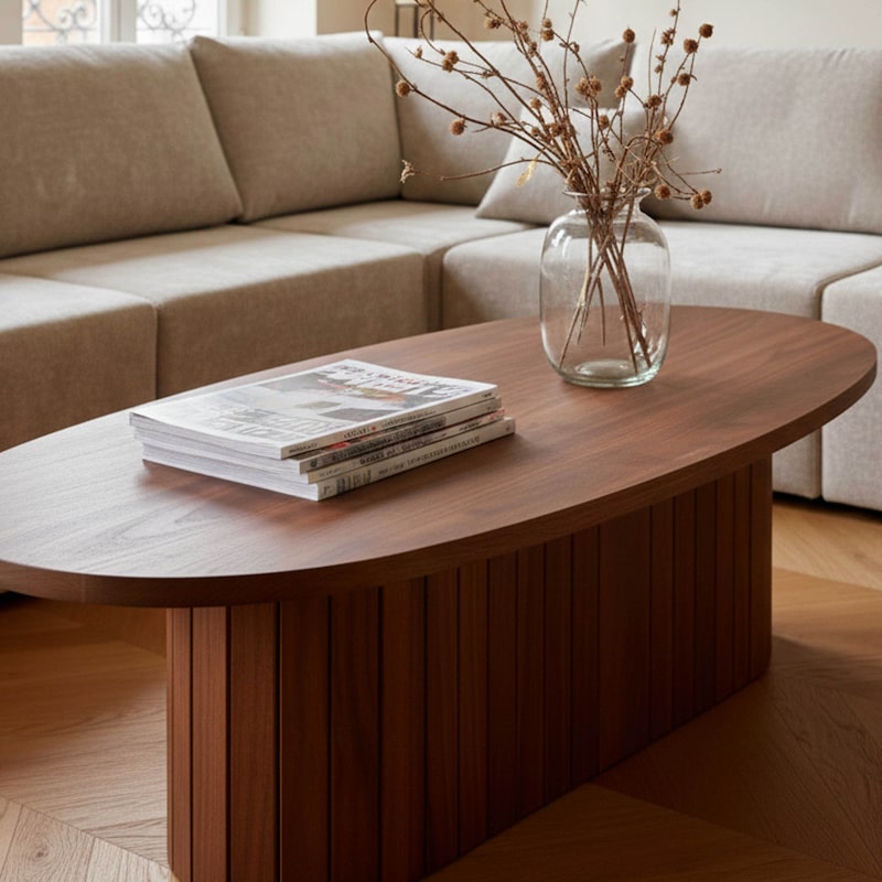 Une table ovale en bois avec magazines et vase.