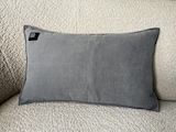 Ein graues Heizkissen auf einem Sofa.
