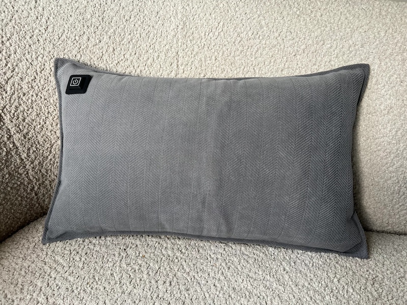 Ein graues Heizkissen auf einem Sofa.