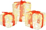 Drei beleuchtete Geschenkboxen mit roten Schleifen.