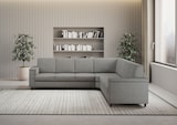 Divano angolare grigio con libreria sullo sfondo.