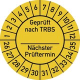 Ein runder gelber Aufkleber mit schwarzen Markierungen.