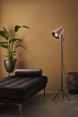 Ein rosafarbener Stehlampe neben einem Sofa.