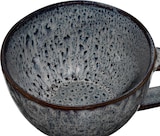 Eine graue Tasse mit braunem Rand.
