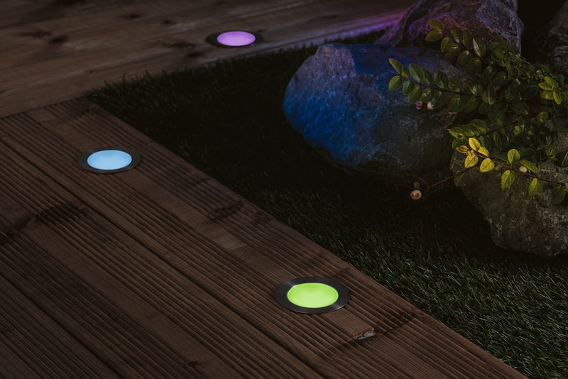Les éclairages au sol illuminent bois et gazon.
