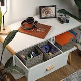 Ein weißes Regal mit Körben und Büromaterial.