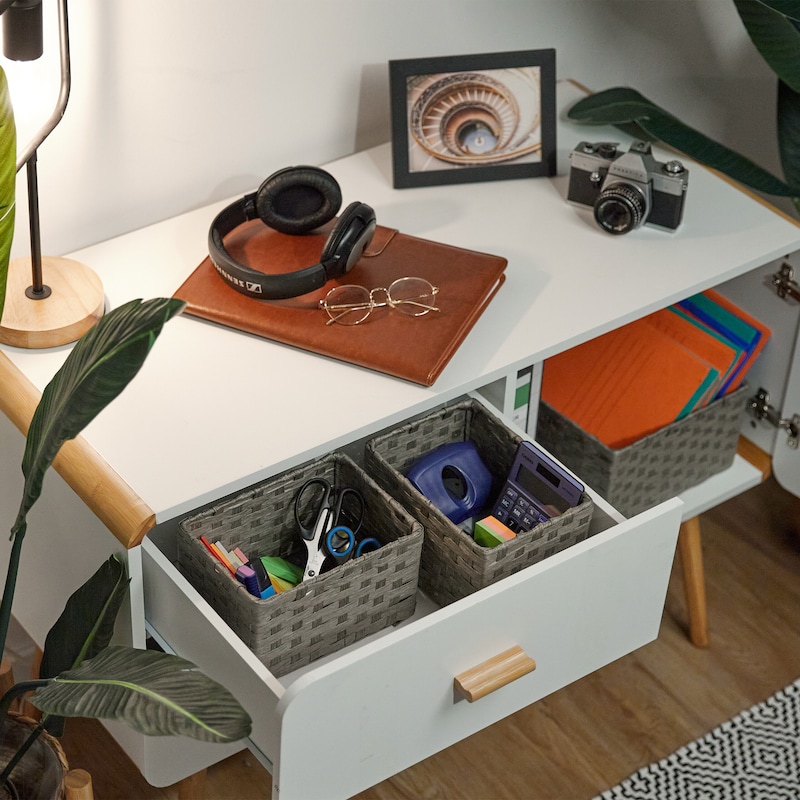 Ein weißes Regal mit Körben und Büromaterial.