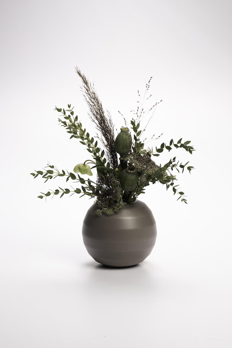 Ein getrockneter Blumenstrauß in einer grauen Vase.