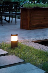 Eine leuchtende Lampe auf einem Rasenweg.