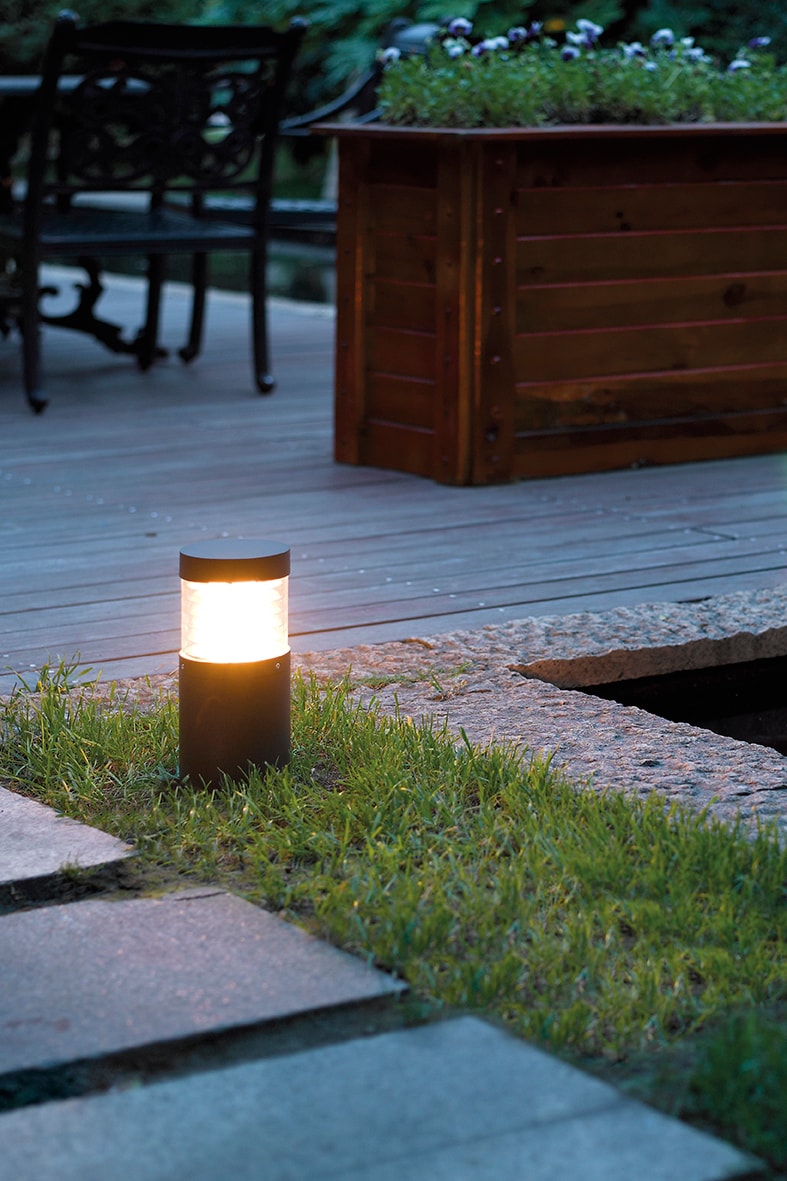 Eine leuchtende Lampe auf einem Rasenweg.